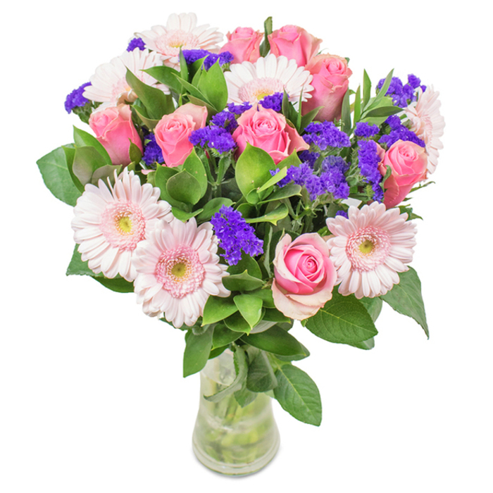 Set on a pristine backdrop, this clear glass vase arrangement radiates the freshness and elegance unique to Berrylands' suburban charm. Approximately 7-9 pink roses, their petals in both tight spirals and graceful half-blooms, form the bouquet's romantic centrepiece. 5-7 pale pink gerbera daisies fan out around them, each blossom with a wide, ruffled crown and almost white, luminous centres. Interwoven are vivid clusters of purple statice, which offer vibrant contrast and a touch of playfulness, reminiscent of Berrylands' lively gardens. Deep green foliage surrounds and enriches the bouquet, providing texture and an abundant sense of life. The visible stems and clear water underscore a natural garden-to-vase presentation, perfect for same-day delivery in Berrylands-be it for birthdays, anniversaries, Mother's Day, or to enhance a welcoming living space. Every flower is selected by Berrylands Flowers for fresh beauty and heartfelt meaning, ensuring joy and celebration are delivered with every bouquet.