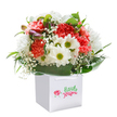 Joy beams from this Berrylands bouquet, perfectly set in a clean, white square gift bag that evokes the spirit of a thoughtful local surprise. Warm coral and lively red carnations blossom at the centre, their ruffled petals shimmering with energy and sending a gentle, inviting fragrance through the air. Cheerful white daisies, each crowned with a vibrant green-yellow center, add freshness and a sense of celebration reminiscent of Berrylands' community events and sunny moments in Shadbolt Park. Artful wisps of baby's breath linger between the blooms, their delicate star-like blossoms lending a light, graceful touch. Deep emerald-green leaves create a lush support, curving protectively around the flowers in a manner that brings to mind the sheltered gardens of the area. Peeking from the side, a few closed buds tinged in twilight purples whisper of blooms yet to open, infusing the display with hopefulness and quiet anticipation. The arrangement's perfectly rounded shape and harmonious colours highlight the care of expert Berrylands florists, making it an ideal choice for birthdays, anniversary surprises, or simply to deliver a dash of beauty to someone's day. With each element bathed in natural light and presented with artistry, this statement bouquet is ready to travel across KT5, brightening Berrylands homes and hearts alike.